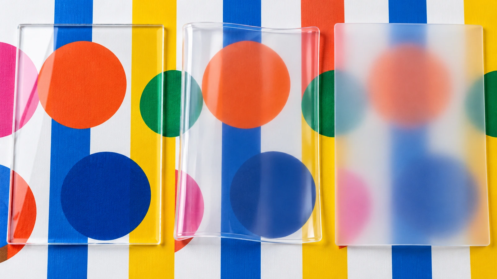 Drei transparente Folienmuster nebeneinander: glasklares PVC, klares weiches TPU und mattiertes transluzentes EVA vor demselben gemusterten Hintergrund