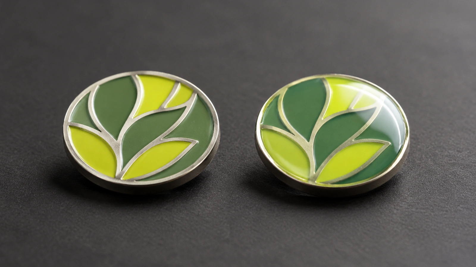 Makro-Seitenansicht zweier Weichemaille-Pins, einer mit strukturierten erhabenen Metallstegen und einer unter einer glänzenden, klaren Epoxidharzkuppe versiegelt