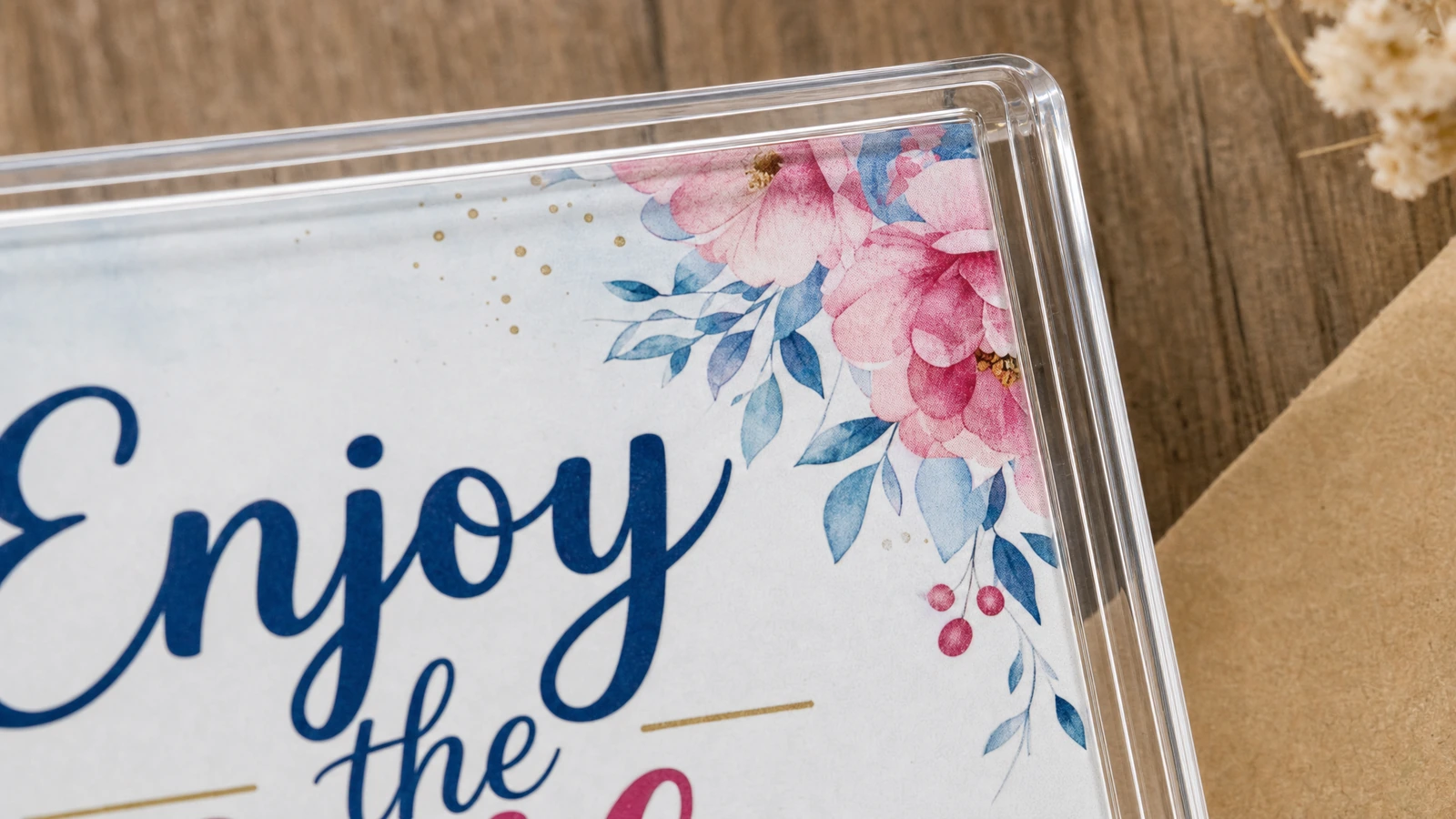Nahaufnahme einer Ecke des klaren Acrylrahmens um einen Zitatdruck mit Blumenmotiv