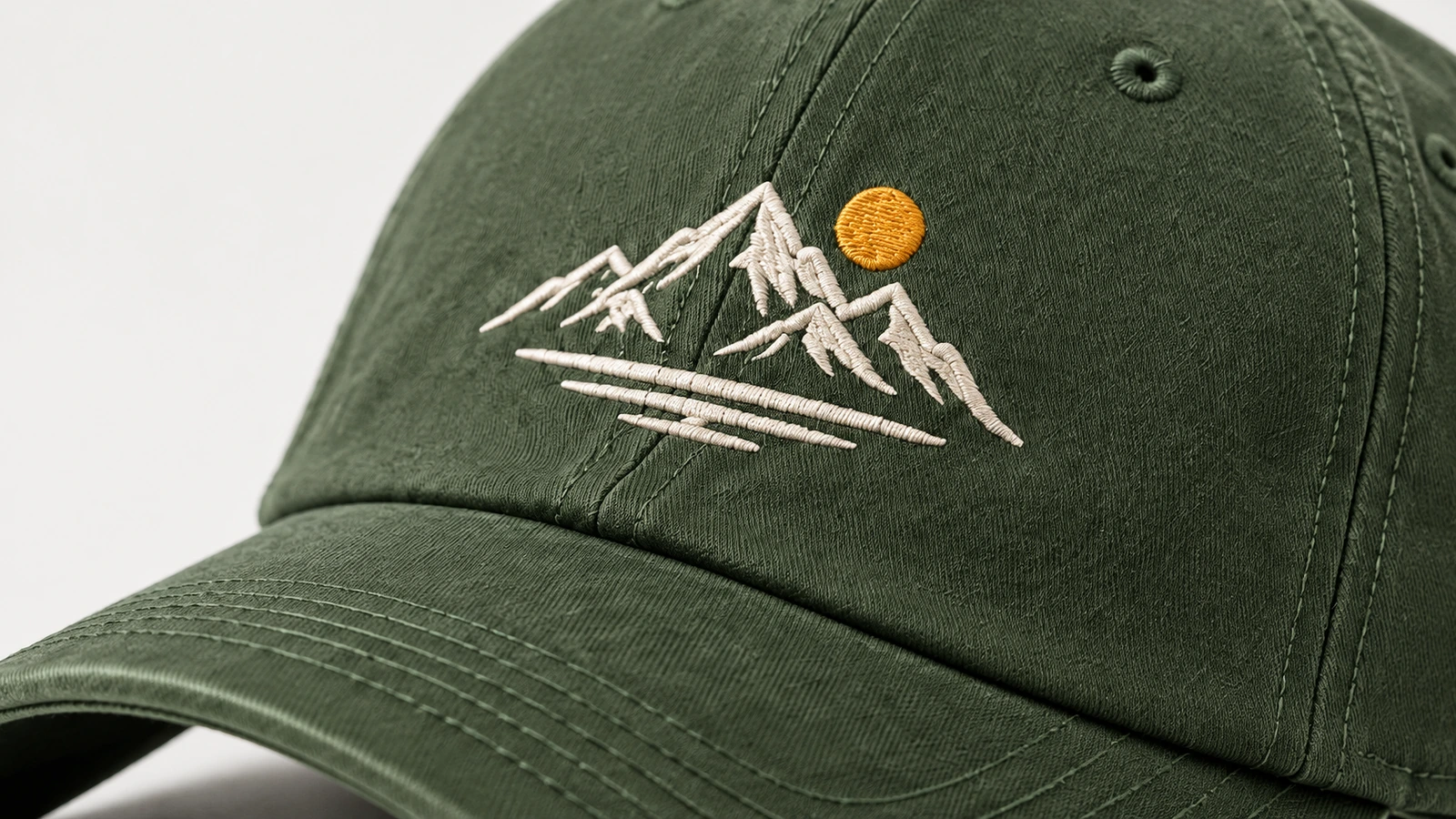 Nahaufnahme einer weißen Bergstickerei und einer gelben Sonne auf einer grünen Cap