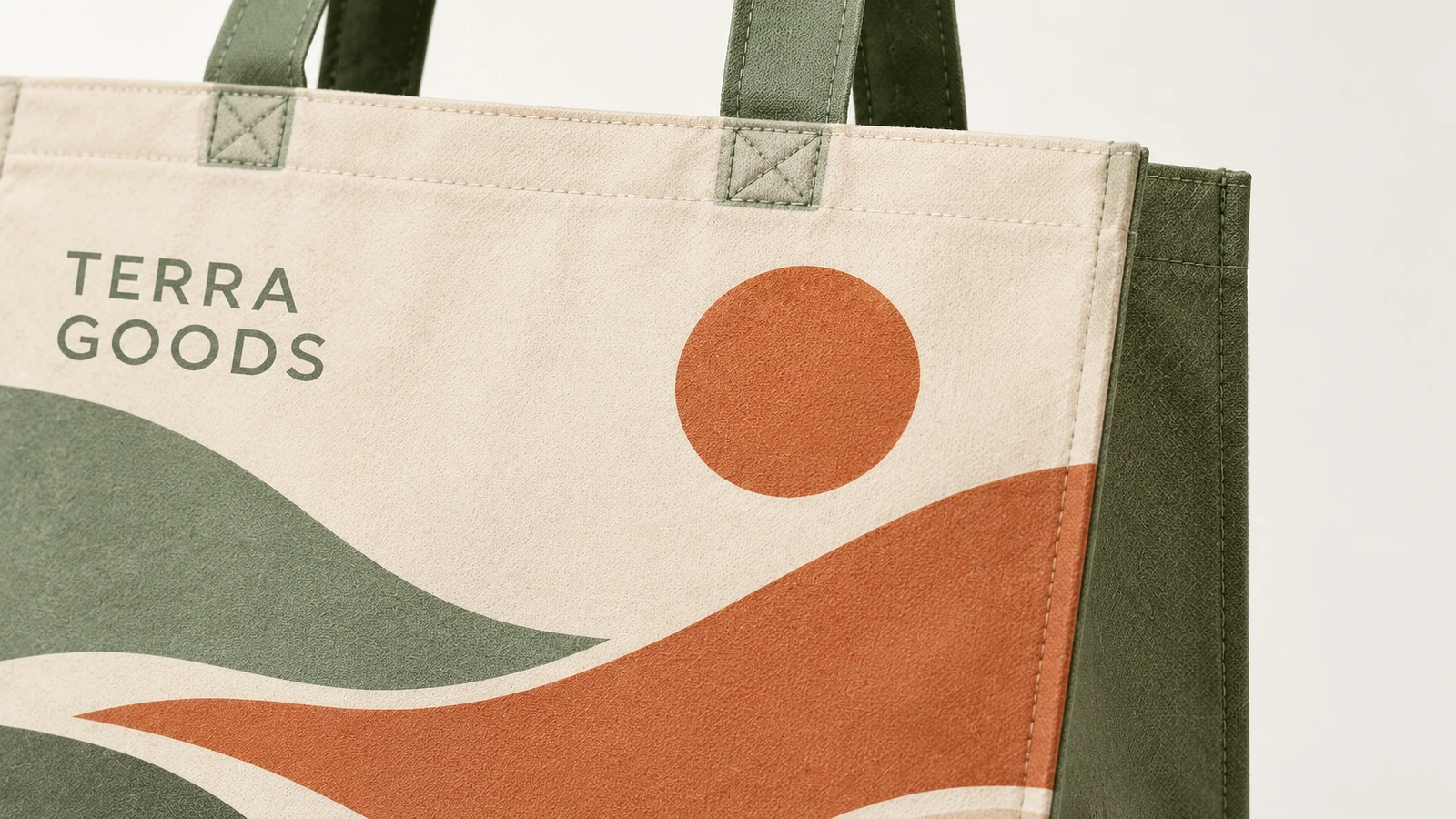 Bedruckte Taschenoberfläche und Henkelnaht Nahaufnahme einer Tragetasche mit Landschaftsdruck, Schriftzug TERRA GOODS und genähten grünen Henkeln