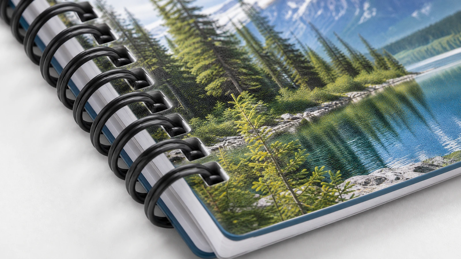 Illustrative Nahaufnahme einer schwarzen Notizbuchbindung und eines bedruckten Covers mit Bergseemotiv