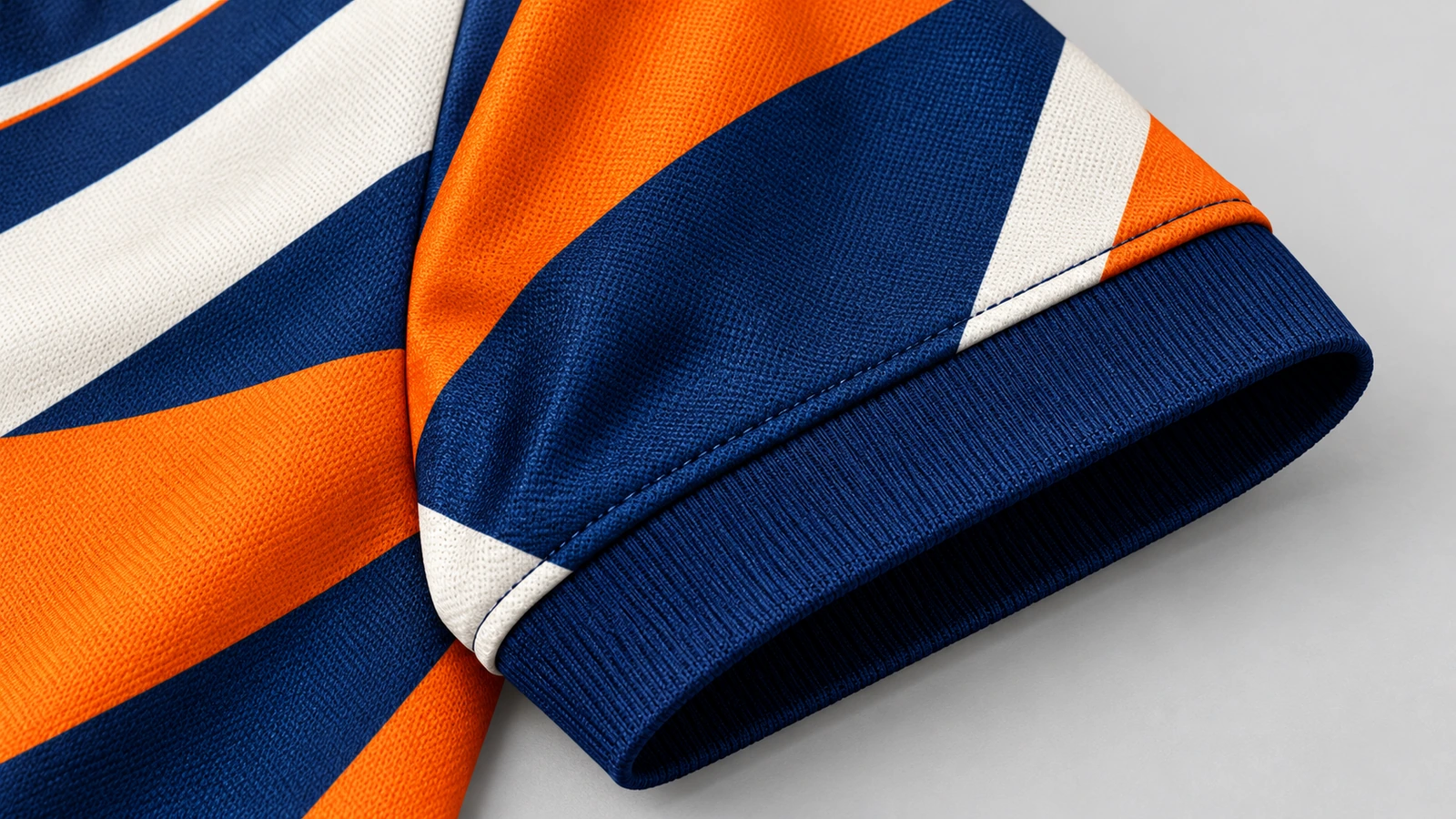 Detail von gemustertem Ärmel und Rippbündchen Nahaufnahme eines gemusterten Ärmels in Orange, Marineblau und Weiß mit marineblauem Rippbündchen